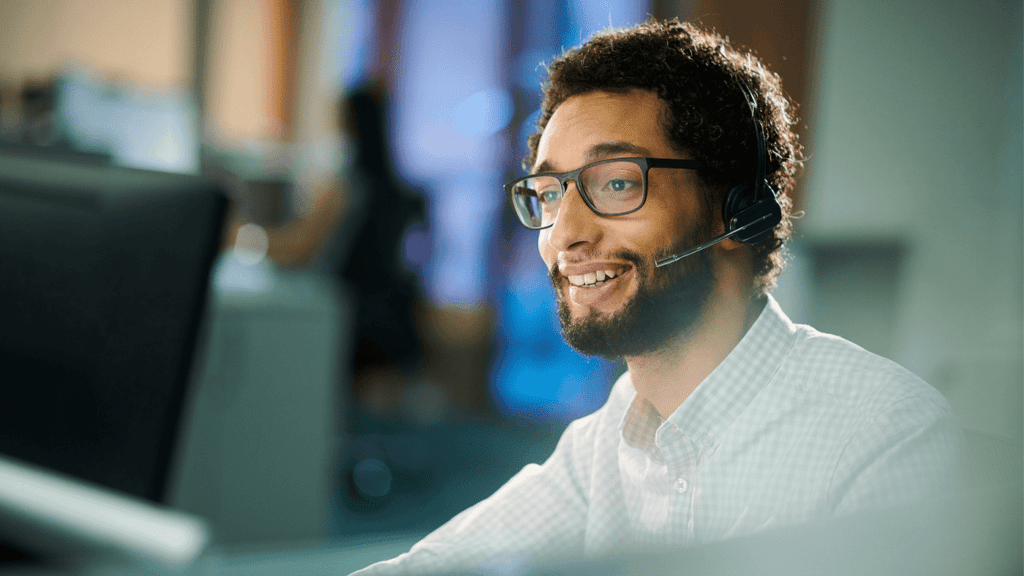 Customer support representative with headset, smiling while assisting clients.