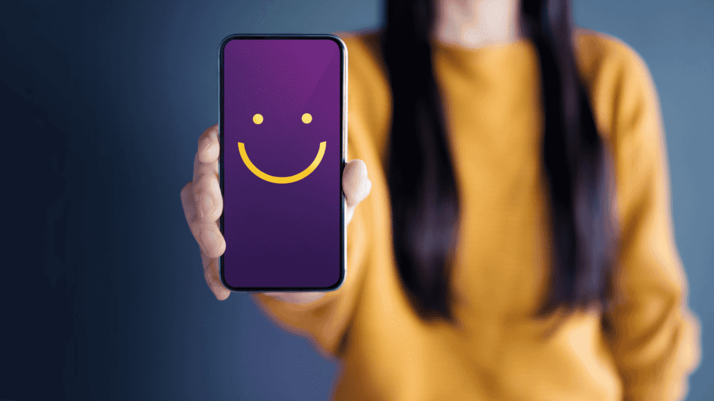 Smartphone screen with a smiley face, symbolising a 24-hour multilingual support hotline.