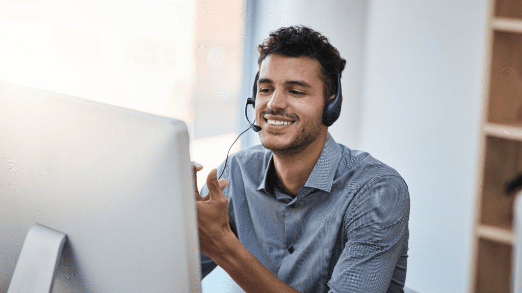Customer support agent with headset in front of a computer, providing international 24/7 support in languages.