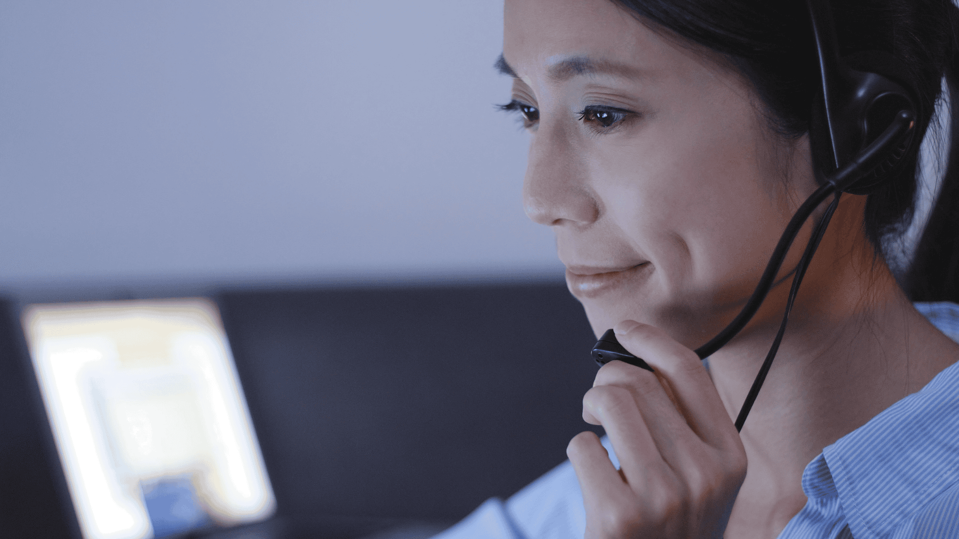 Customer support agent with headset working attentively in a round-the-clock multilingual call centre.