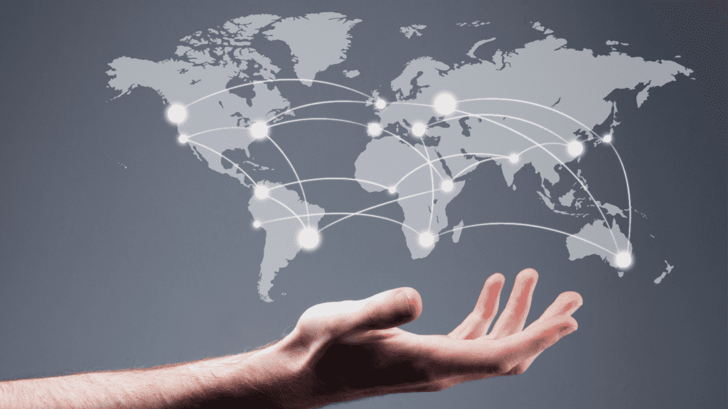 A hand holding up a digital map with illuminated global connections linking countries around the world