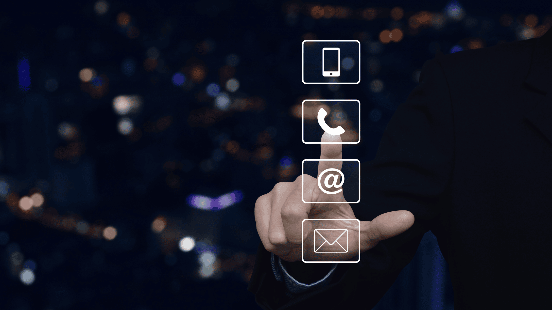 A hand selecting a communication icon (phone, email, and mobile) in a modern digital interface against a cityscape background
