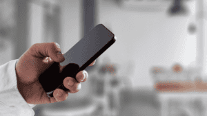 A close-up of a hand holding a smartphone, symbolising accessibility to a multilingual customer care hotline.