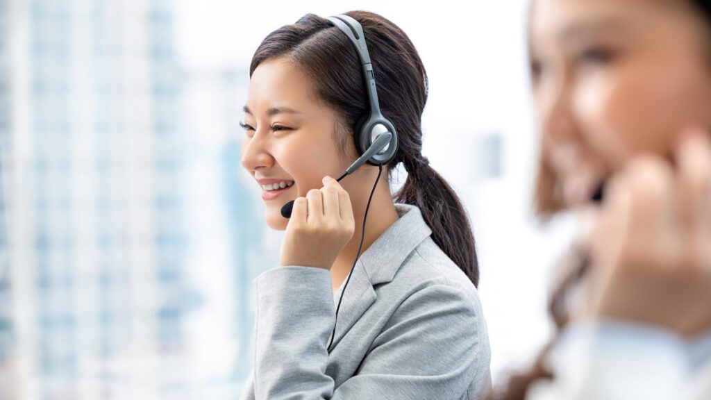 Professional customer support agent providing 24/7 global language support services with a headset in a modern office.