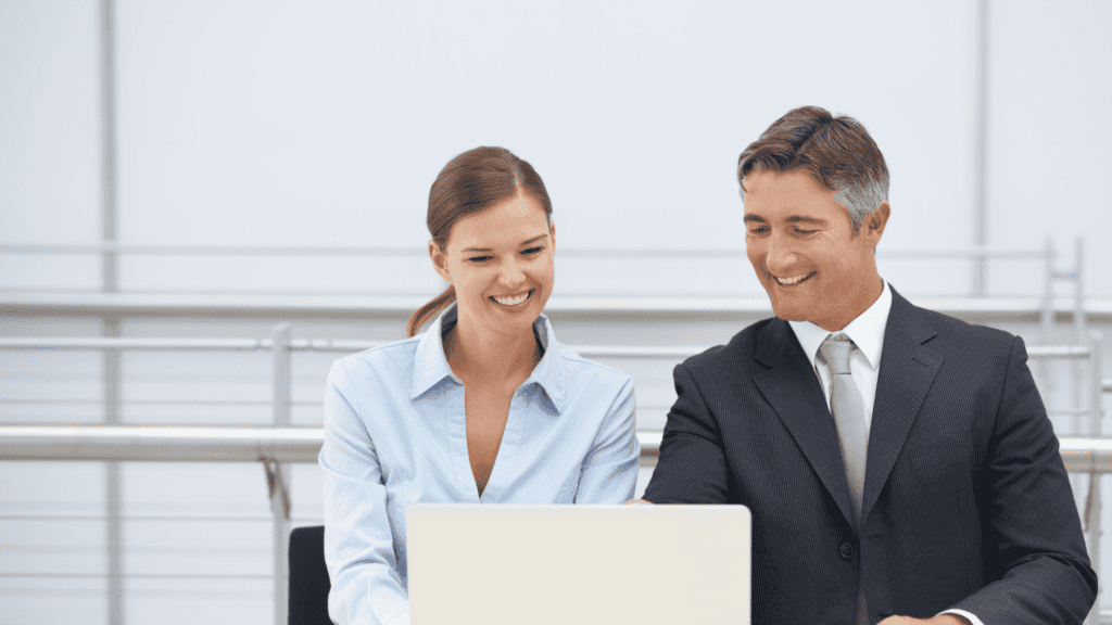 Two professionals discussing on a laptop, symbolizing collaborative multilingual customer care round clock.
