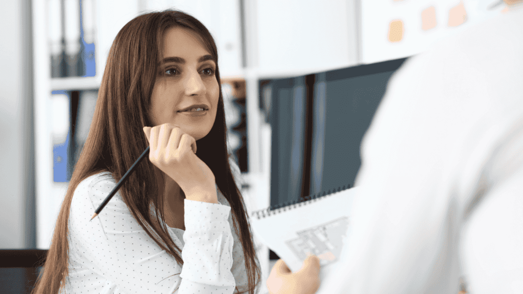 A professional holding a pencil and discussing plans, representing thoughtful multilingual customer care round clock.