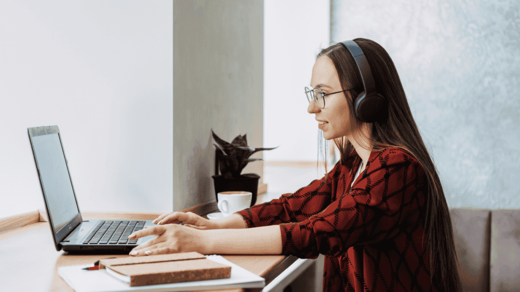 A remote worker wearing a headset, engaged in a task on a laptop while sitting in a modern workspace.