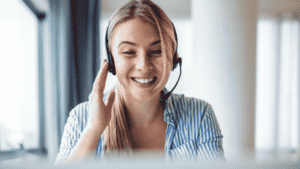 Smiling customer service representative wearing a headset, engaging in a virtual support session.