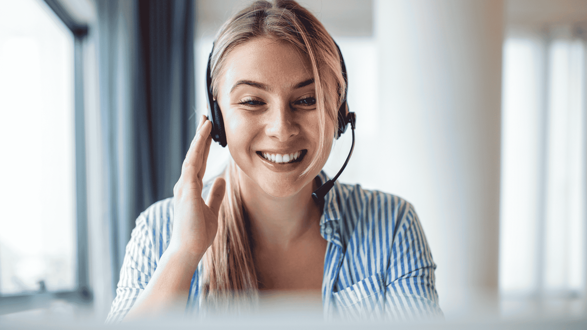 Smiling customer service representative wearing a headset, engaging in a virtual support session.
