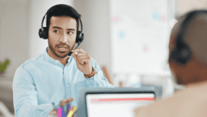 A customer support representative wearing a headset, actively engaging in a conversation while assisting a client.
