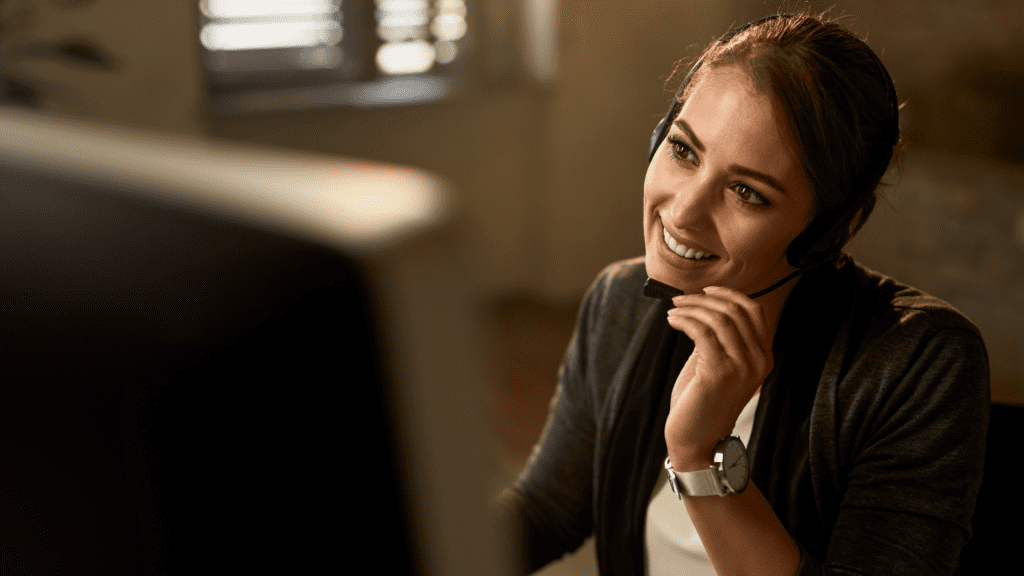 Friendly customer service agent with a headset, attentively listening to a customer query in a relaxed environment.
