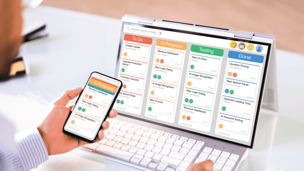 A person using a smartphone and tablet displaying a task management board with "To Do," "In Progress," "Testing," and "Done" columns.