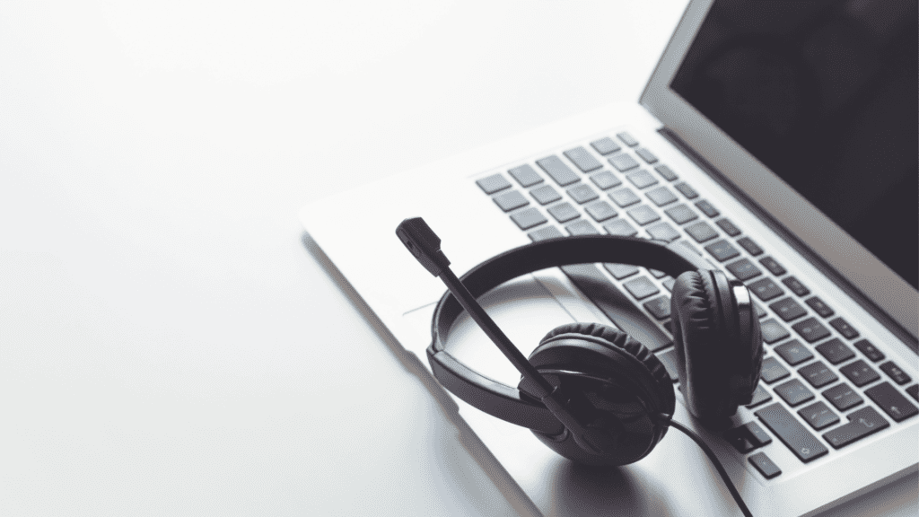 A black headset resting on a laptop keyboard, symbolising remote customer support and multilingual back-office solutions.