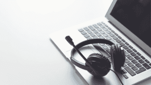 A black headset resting on a laptop keyboard, symbolising remote customer support and multilingual back-office solutions.