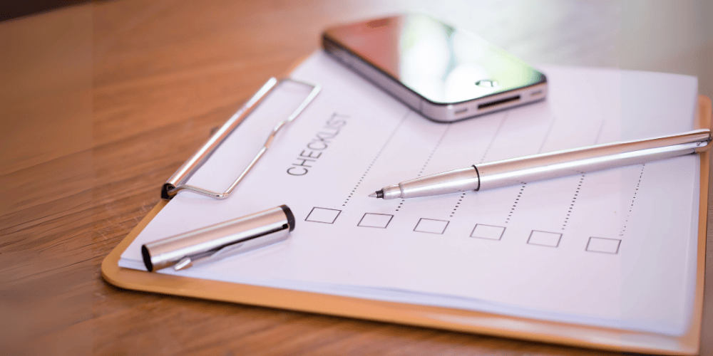 Paper checklist on clipboard with a pen and smartphone, symbolising compliance audits and internal reviews.